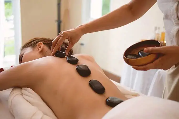 Hot Stone Massage therapy at Orange Spa Dubai with warm basalt stones for deep muscle relaxation.